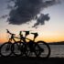 Two bikes parked at the beach at sunset